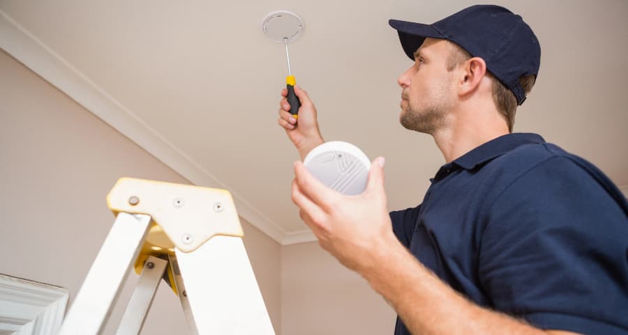 Man putting smoke alarm on ceiling